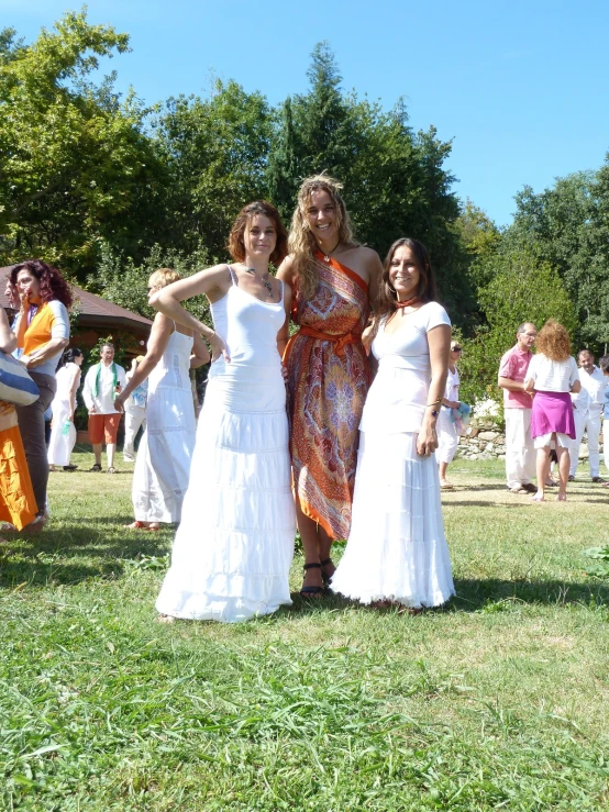 a group of ladies in white dresses standing on some grass