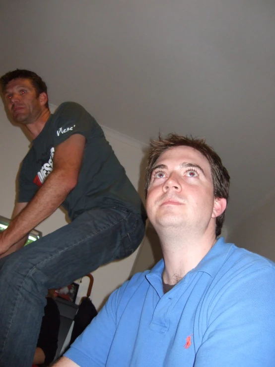 two men standing in a room looking up into the air