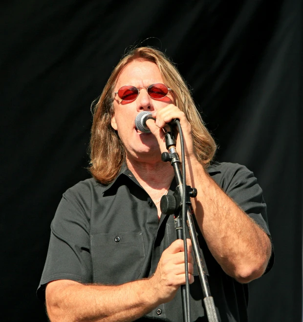 a man in shades sings into his microphone