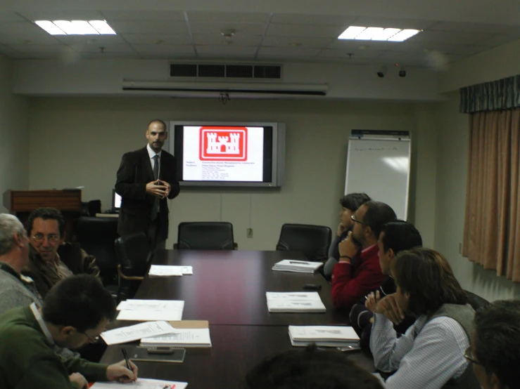 a man standing in front of a class of people in a room