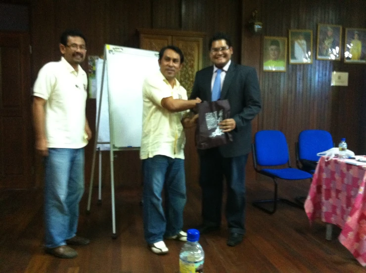 three men posing with a man giving the thumbs up