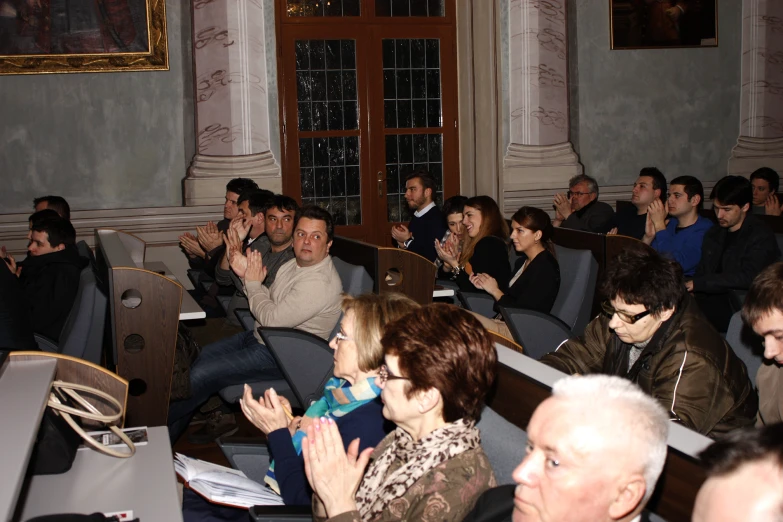 a room full of people, both listening and clapping