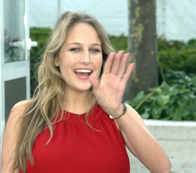 a woman waves to someone holding her hands up