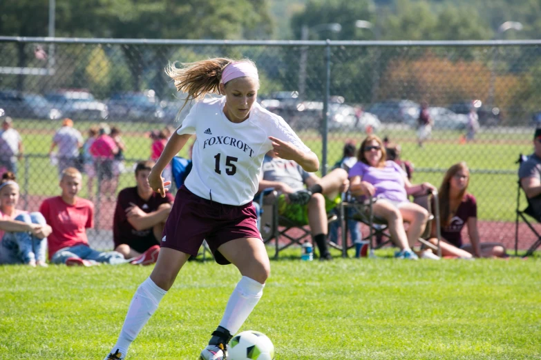 girl with ponytail wearing maroon shorts and soccer jersey