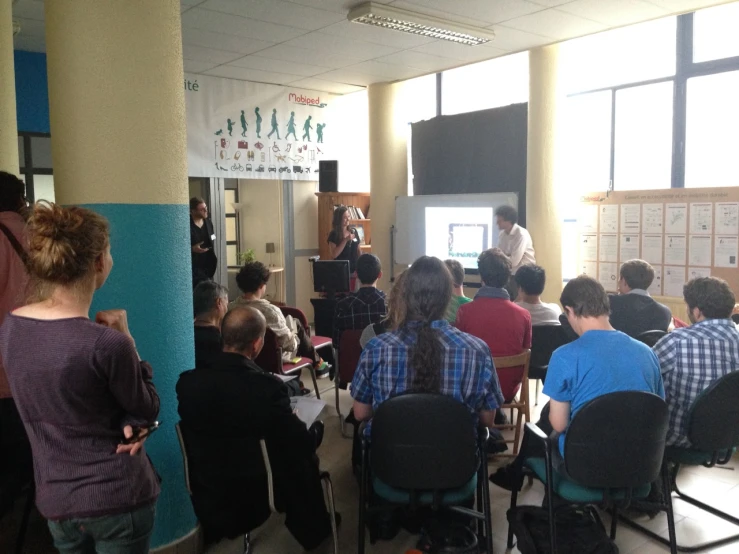 some people are sitting in chairs and one man is giving a presentation