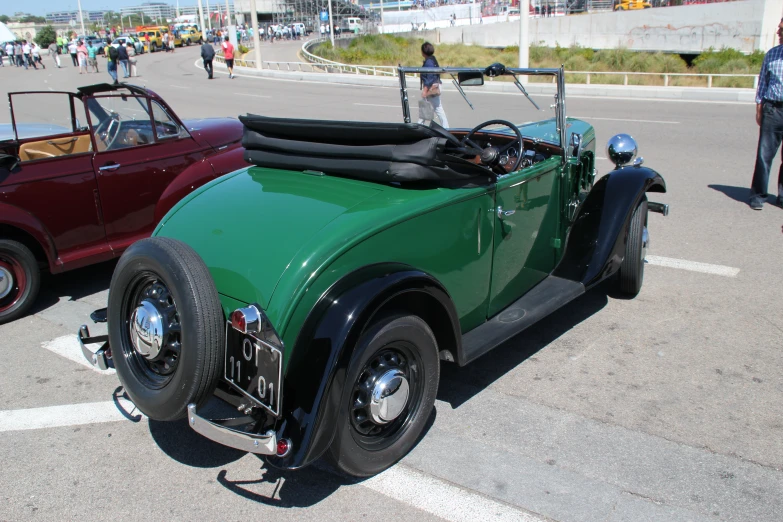 a old green and red car sitting next to a purple car