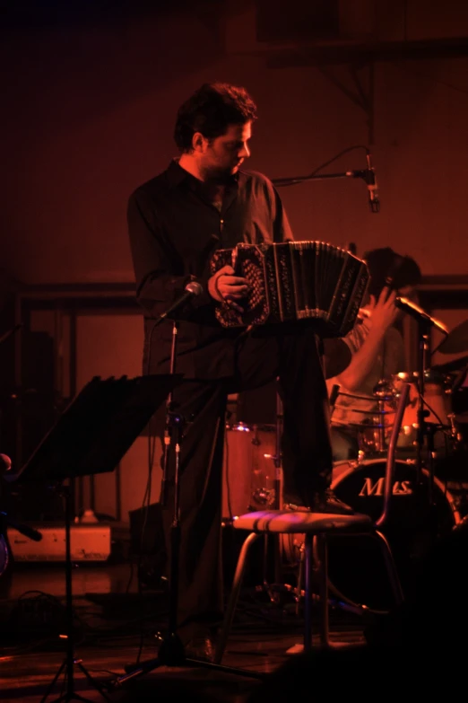 a man playing an accordion in a stage with musicians