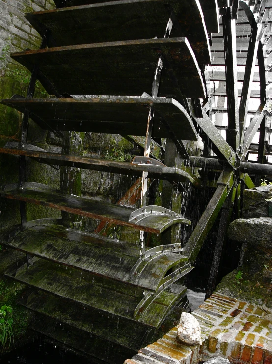 a large wheel sits at the top of a water fall