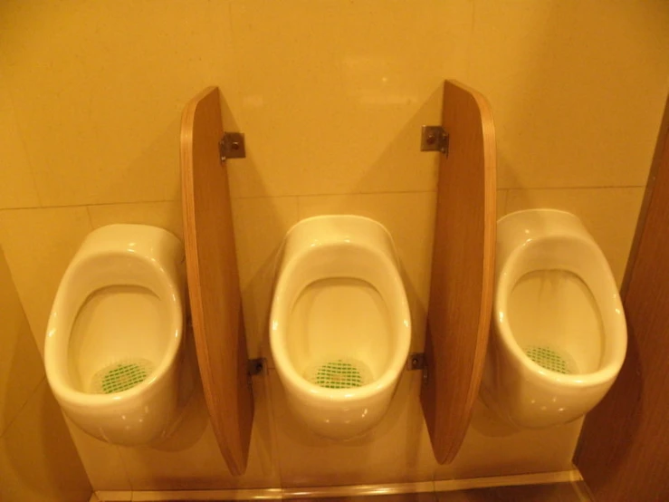 two wooden urinals stand on tiled floor next to one another