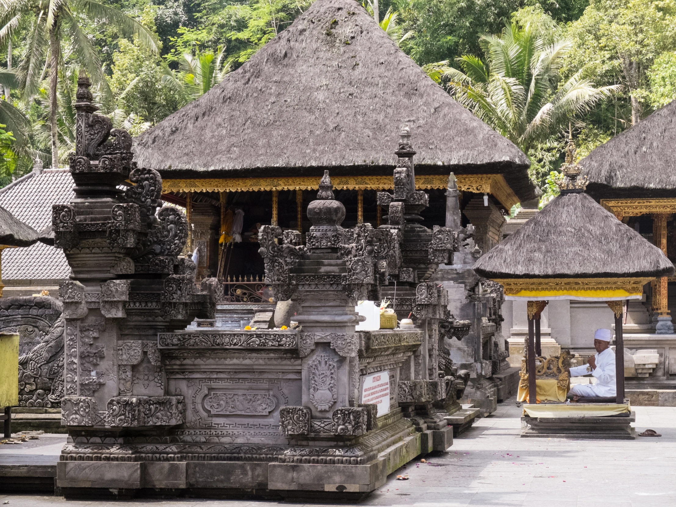 statues on pillars stand in front of an outdoor temple