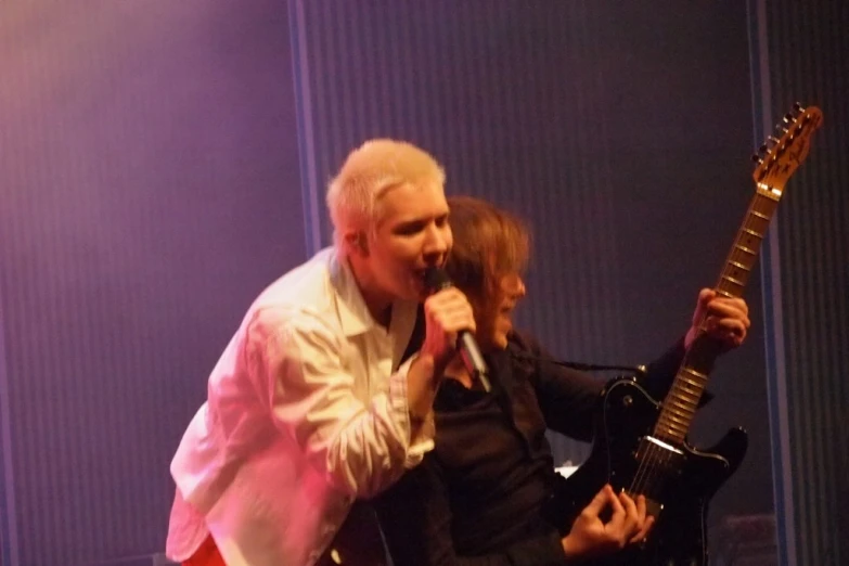 man and woman are standing in front of a microphone, singing