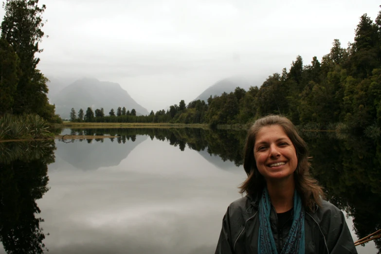 a woman is on a boat near a mountain lake