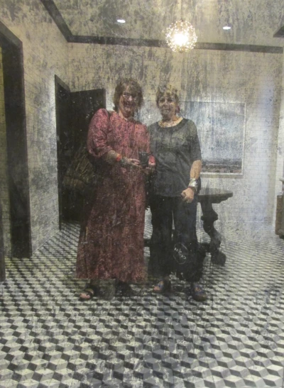two woman in long dress stand under a rain shower