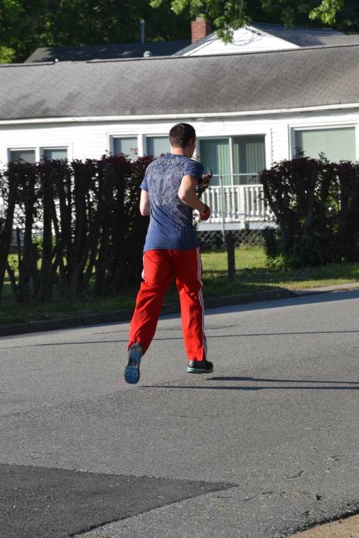 a man wearing red pants running across a street