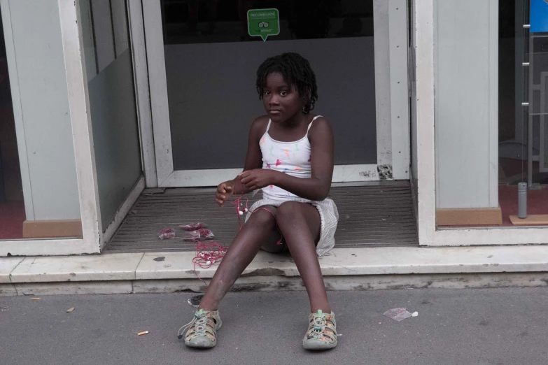 a girl in a white dress sits on the steps near a broken pink object