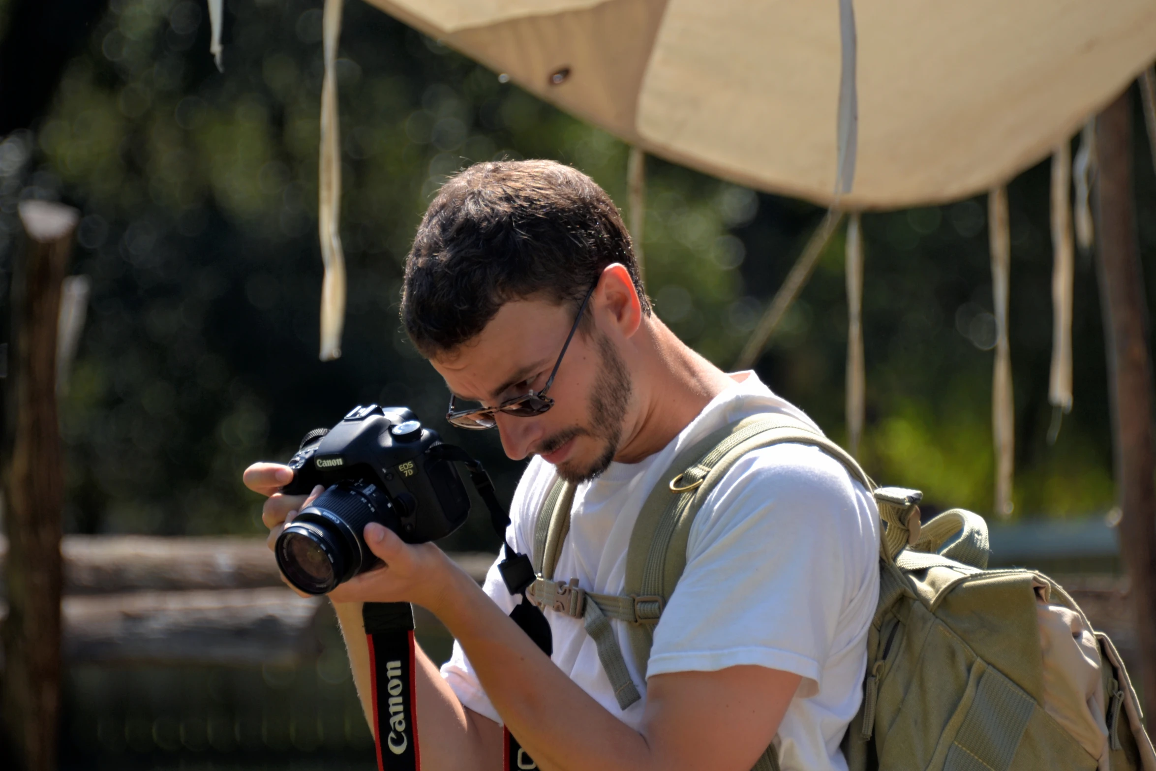 a man with glasses looking down on his camera