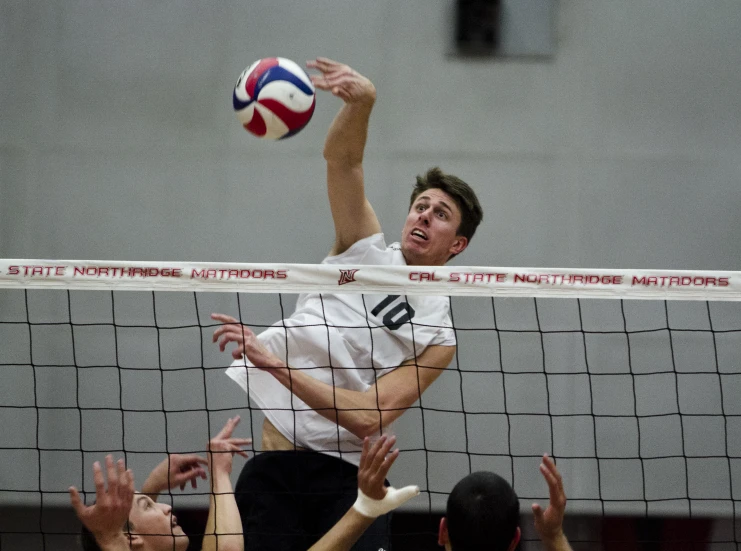 a volleyball player jumps up to hit the ball