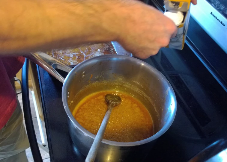 a person pouring soing into a pan on a stove