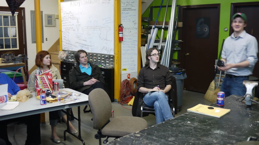 some people sitting down in front of a white board with writing on it