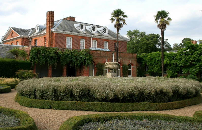 large brick building surrounded by shrubbery and palm trees