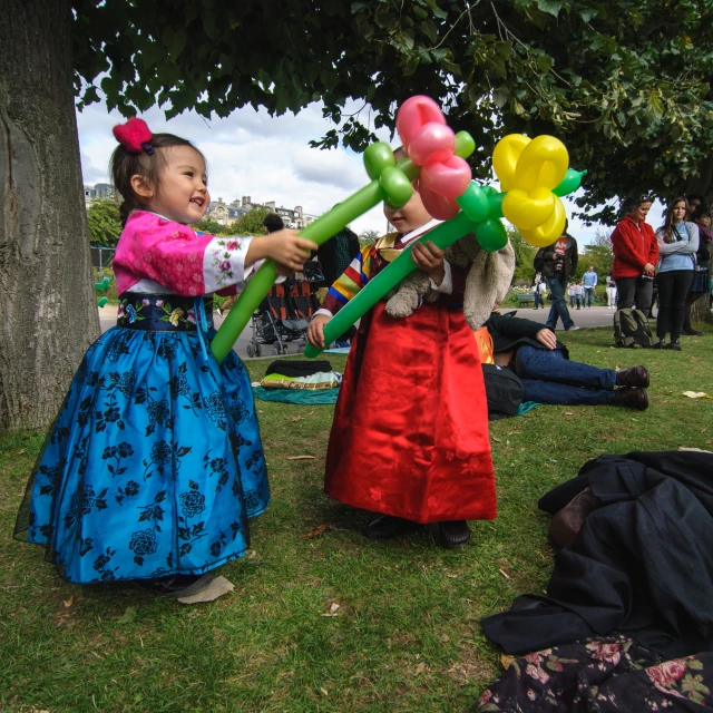 two girls dressed in costumes with balloons and a kite