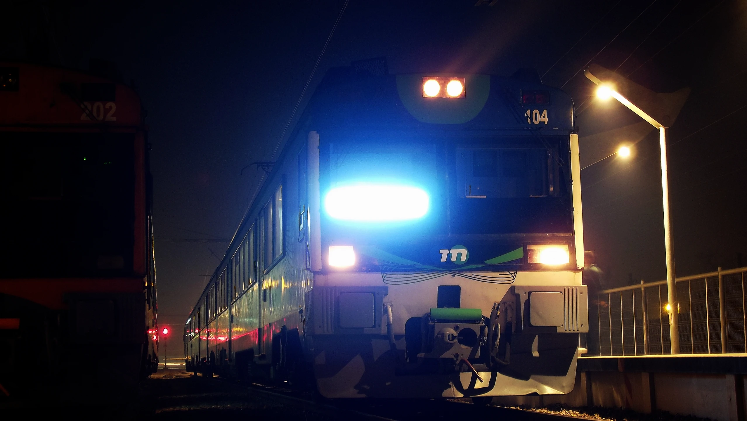 a train with its lights on traveling down the railroad tracks