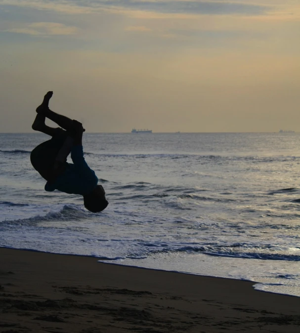 the man is doing a flip trick at the beach