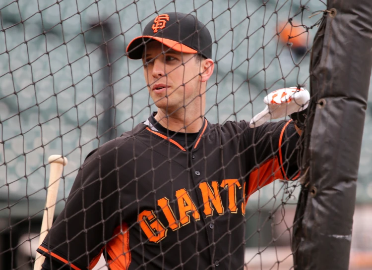 a professional baseball player stands on the sidelines