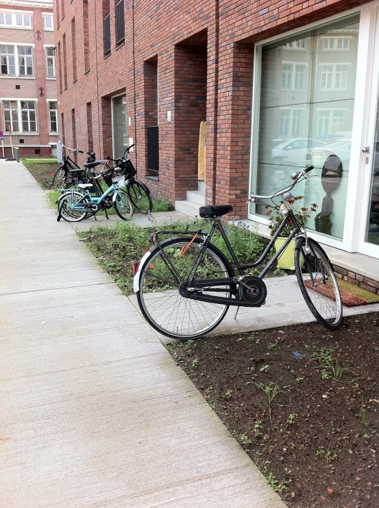 bikes parked on the curb beside buildings and grass