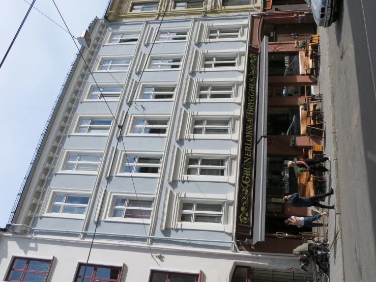 people walk down the sidewalk past tall buildings