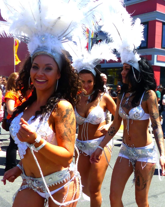 a group of bikini clad women in white outfits are performing parade style