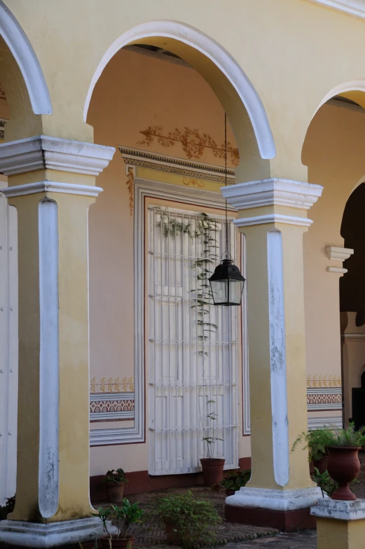 three pillars outside of an ornate building with a large white door and lantern fixture