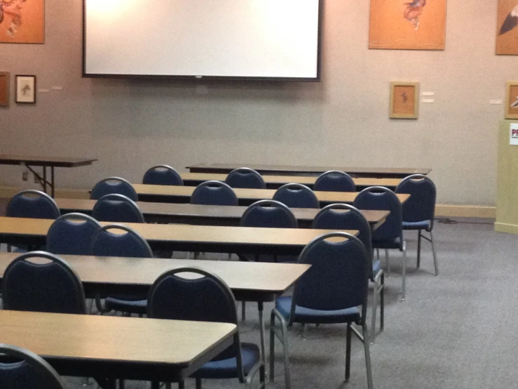 a lecture room with blue chairs and a projector screen