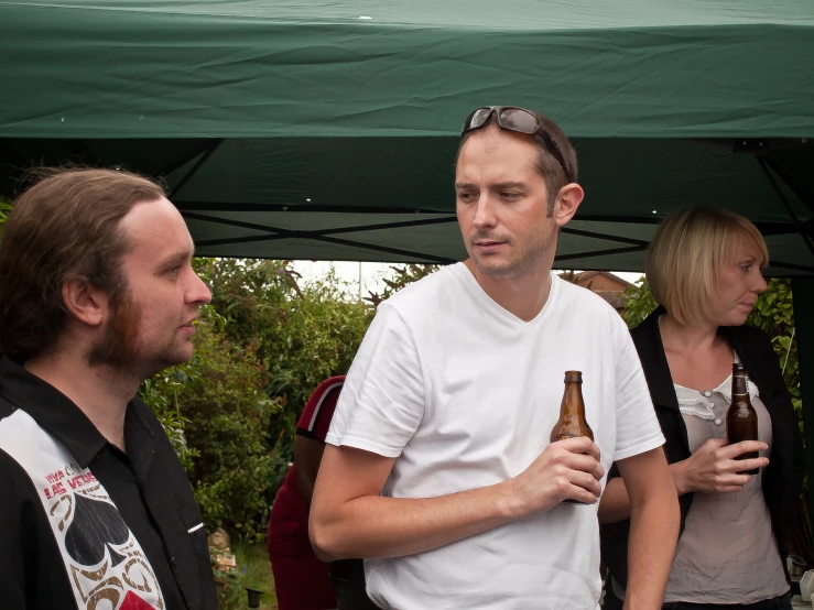 three men talking to each other while holding bottles