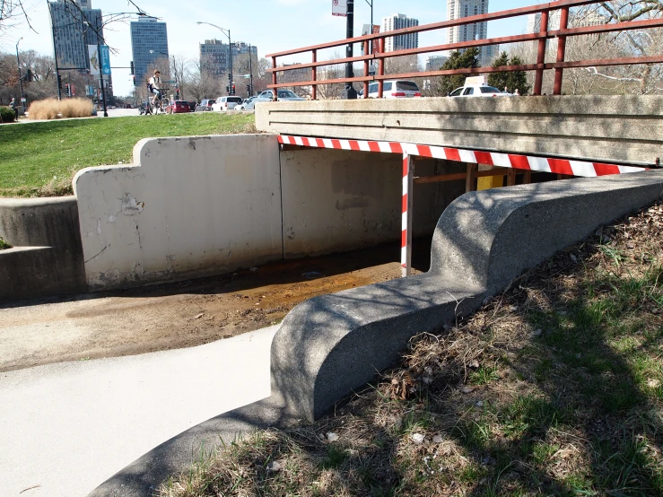 the side of a sidewalk near the water and bridge