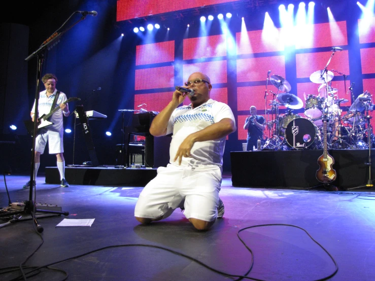 a man in white shirt and shorts standing on stage