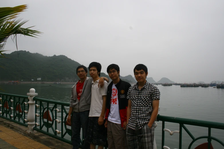 a group of young men on the shore next to a body of water