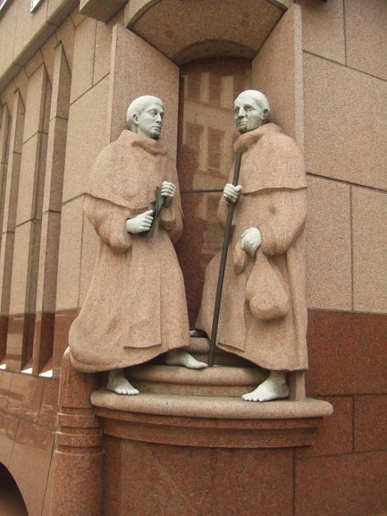two statues in front of a stone building