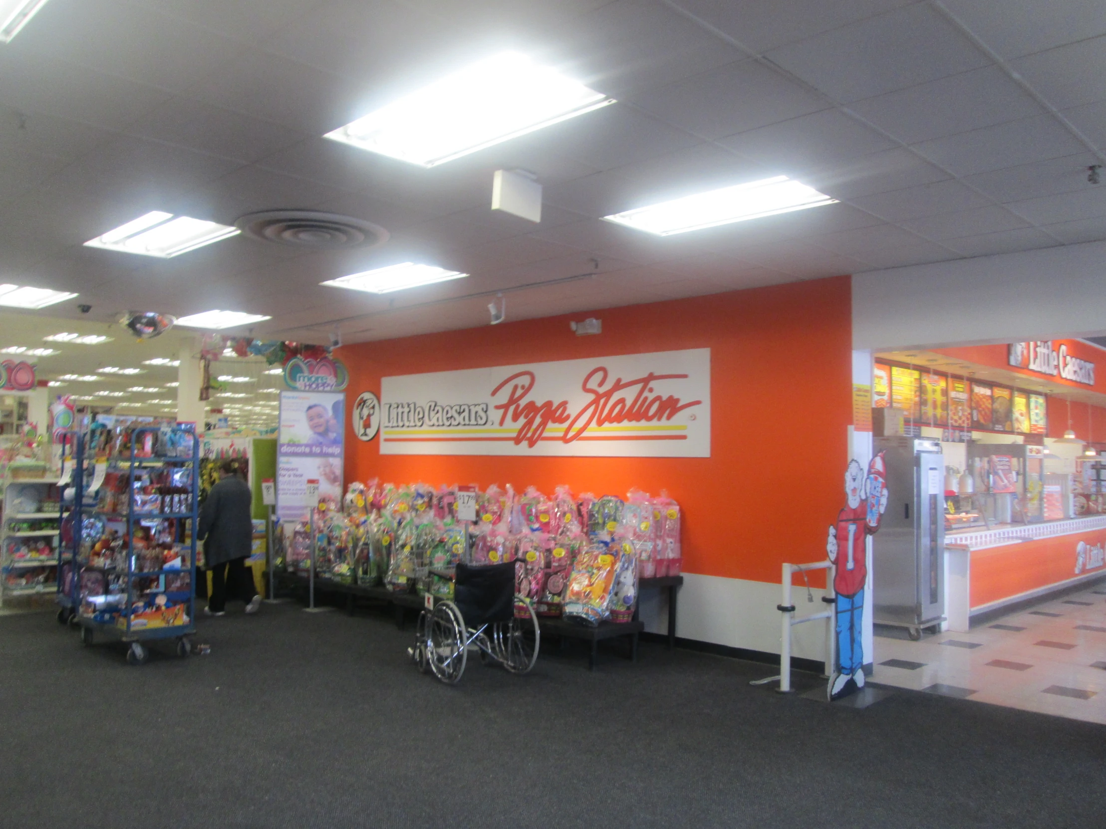 a grocery store with an orange wall and a man hing a cart