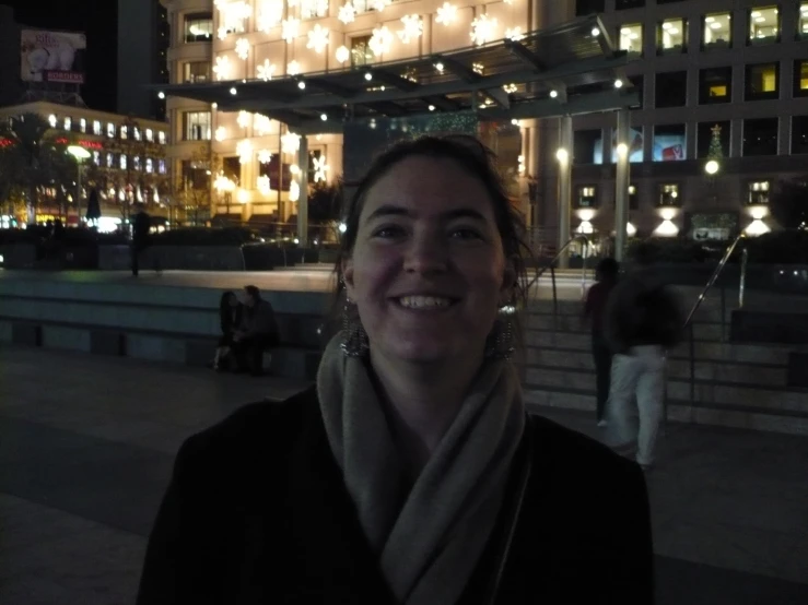 a woman smiling at the camera near some lights