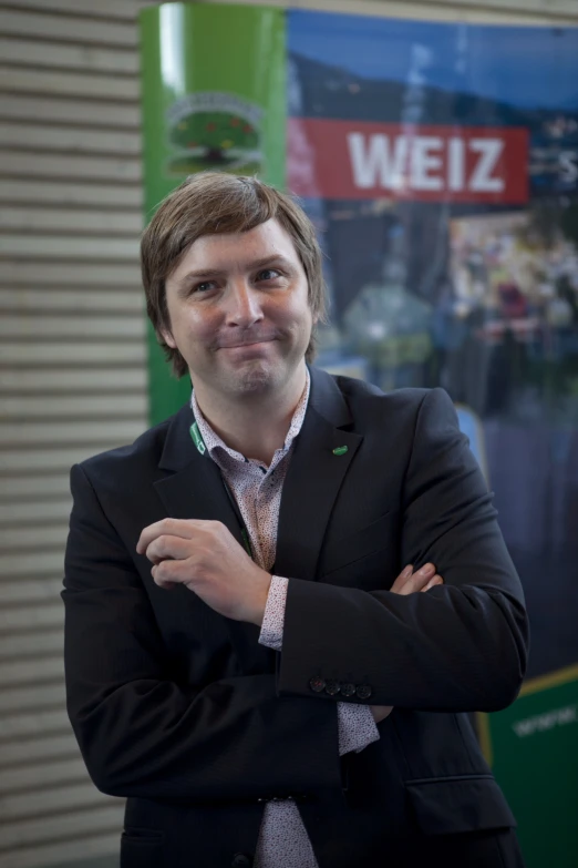 a man in a business suit smiling with his arms crossed