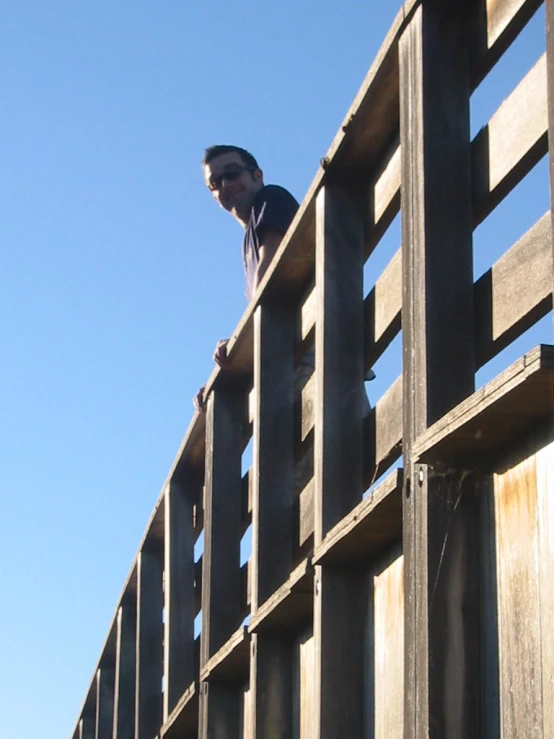 a man standing on top of a wooden railing