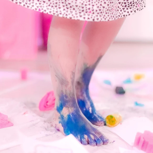 a child's feet with blue, white, and purple paint on it