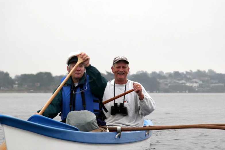 two men smile while sitting in a small boat