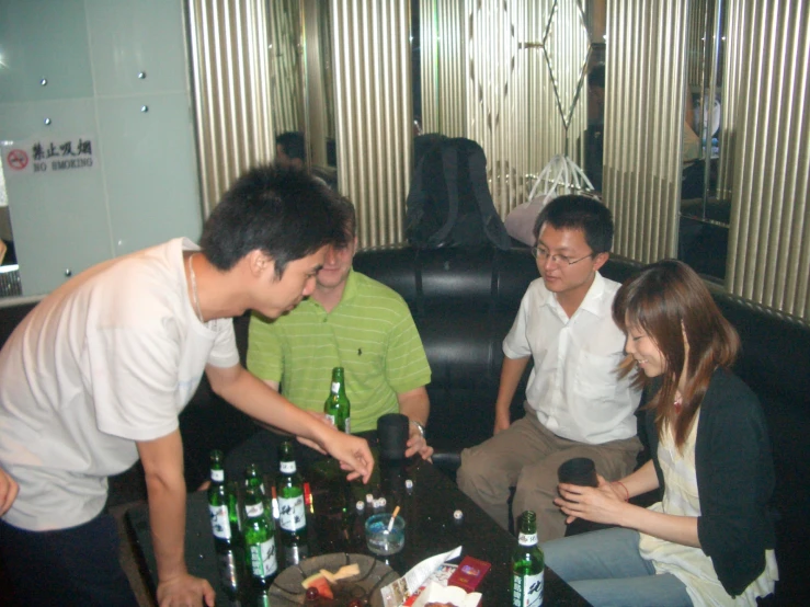 a group of asian men sitting around drinking bottles
