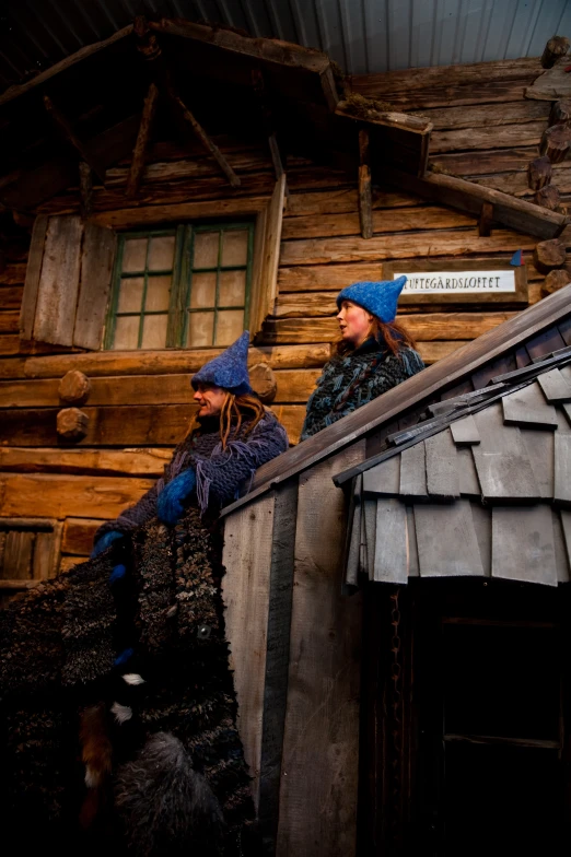 two women wearing winter clothing standing on a roof