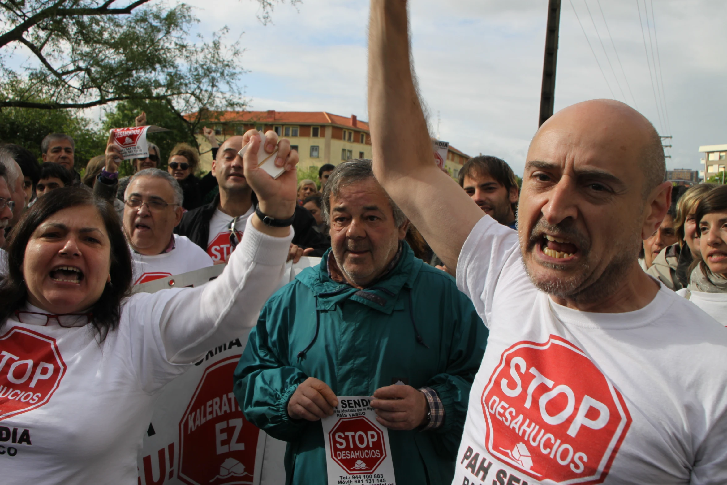 several people are gathered in the middle of the street, while one man is yelling at the camera