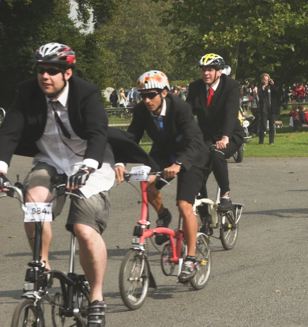 two men and a woman ride bicycles along the park