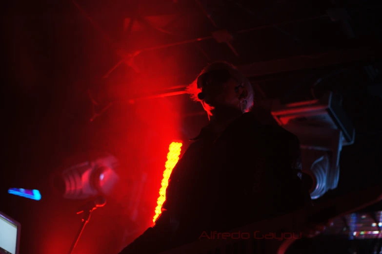 a man standing in a dark room with light up in the background