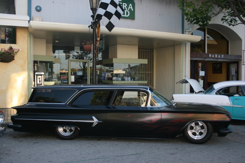 a black and silver car sits in front of an auto show